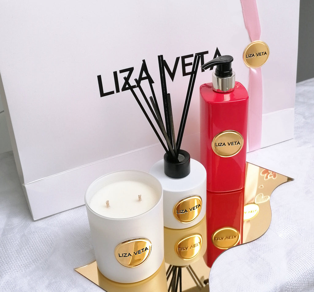 A gift set with white branded paper bag and white candle, white reed diffuser and red Neroli hand and body lotion. This image is related to the post about how to choose a perfect gift for any occasion.