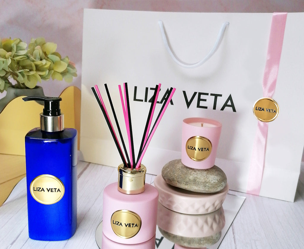 This is a gift set with white branded bag, jasmine hand and body lotion in blue packaging, pink small candle and pink aromatherapy reed diffuser. This image is related to how to choose a perfect gift.