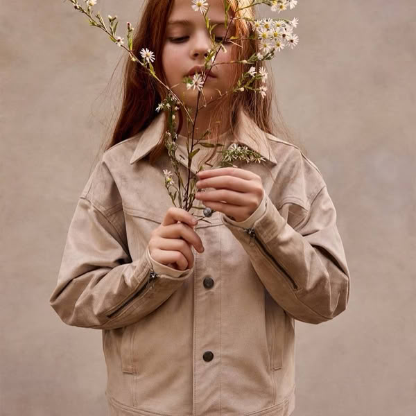 Child walking through a green field wearing organic clothing, symbolizing a hopeful and sustainable future.