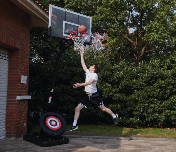 An image of a basketball player going for a layup on an IE Sports basketball hoop on a sunny day.