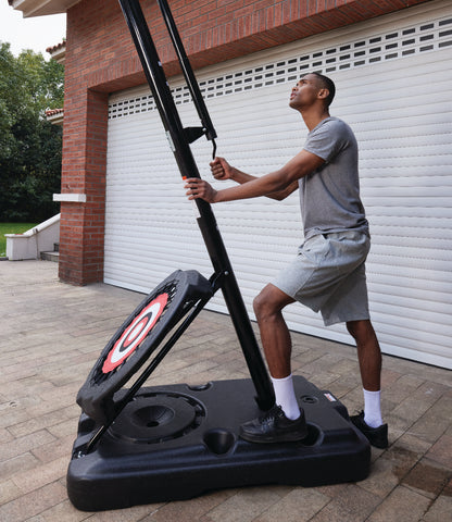 Man adjusting the height of a portable basketball hoop simply by using the crank.