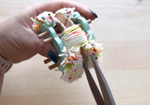 cutting the yarn on a Pom Maker