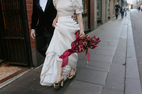 bride walking in melbourne city with bright red bouquet