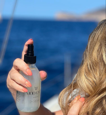 spraying sea salt spray into hair on a boat