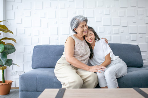 Asian grandma and granddaughter hugged with happy mood on the sofa in home