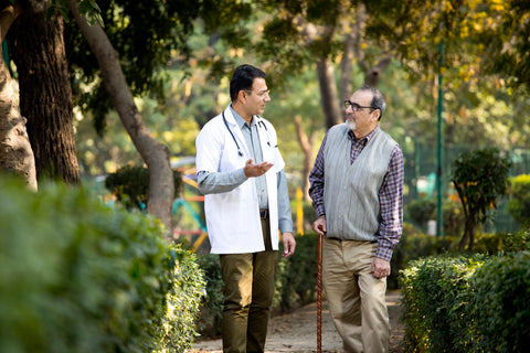 Friendly doctor taking care of senior man walking in the hospital garden