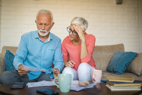 Senior couple at home managing their finances whilst sitting on the sofa