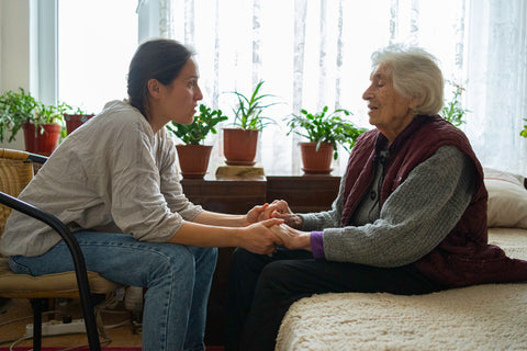 Senior woman holding hands with her adult daughter and talking with empathy