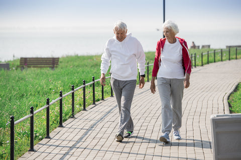 active senior couple walking well in park and smiling happily while chatting on the way