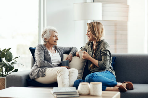 senior woman and her adult daughter sitting together at home and talking