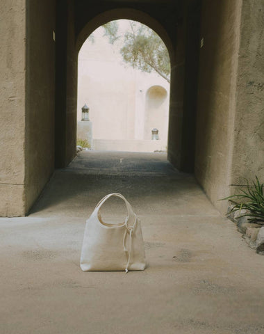 Artistic shot of a reusable bag by Enso Design Lab, placed outdoors in an archway. Designed by Creative Director Ani Han, the bag emphasizes sustainability and can be used multiple times. Keywords: reusable bag, sustainable fashion, Enso Design Lab, Ani Han, eco-friendly design.
