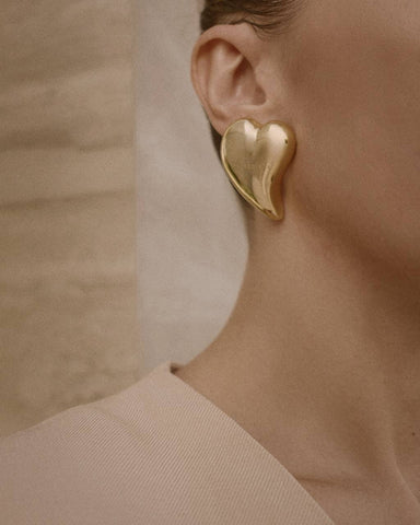 Close-up of a model wearing a statement earring in the shape of a liquid heart, designed by Enso Design Lab's Creative Director Ani Han. The earring symbolizes the brand's unique and artistic approach to jewelry design. Keywords: statement jewelry, designer earrings, unique jewelry, Enso Design Lab, Ani Han.