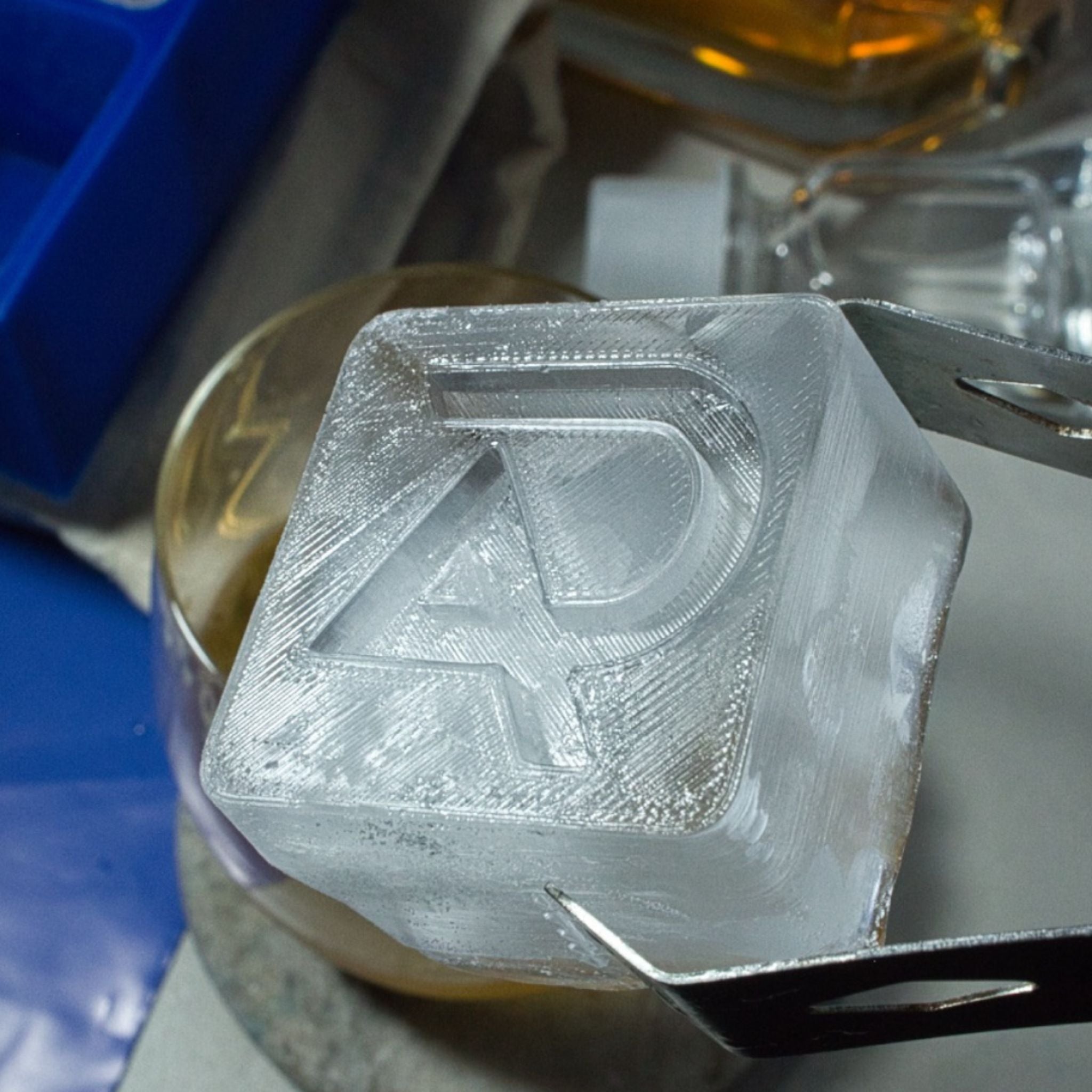 Custom monogram ice cube with “AD” logo embossed in clear ice, designed for luxury drink service.
