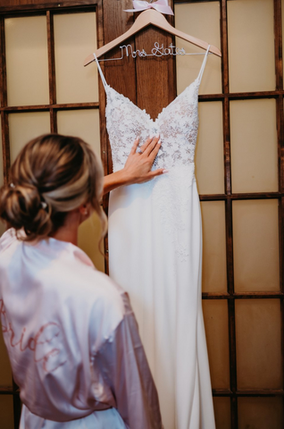 Bride admiring her wedding dress before getting dressed on her wedding day