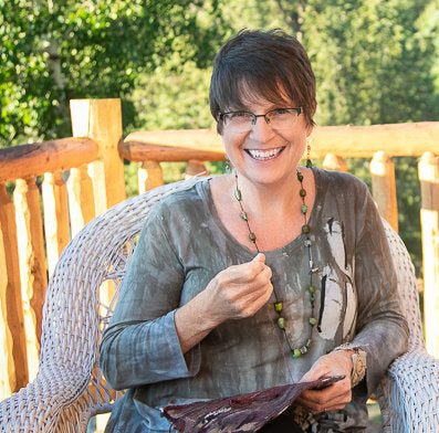 liz kettle sitting in a chair outside in the mountains stitching