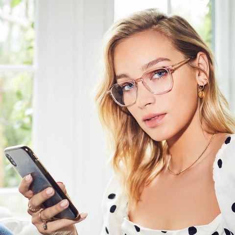 Noel eyeglasses with vintage crystal frames and blue light technology lens on a female model holding a phone