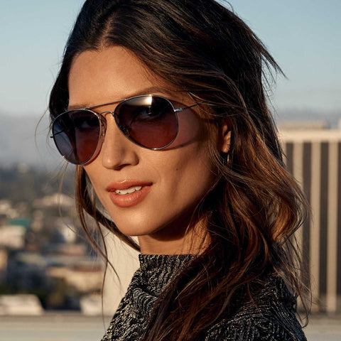 Woman wearing dress on metropolitan rooftop as sun is setting wearing DIFF Cruz sunglasses