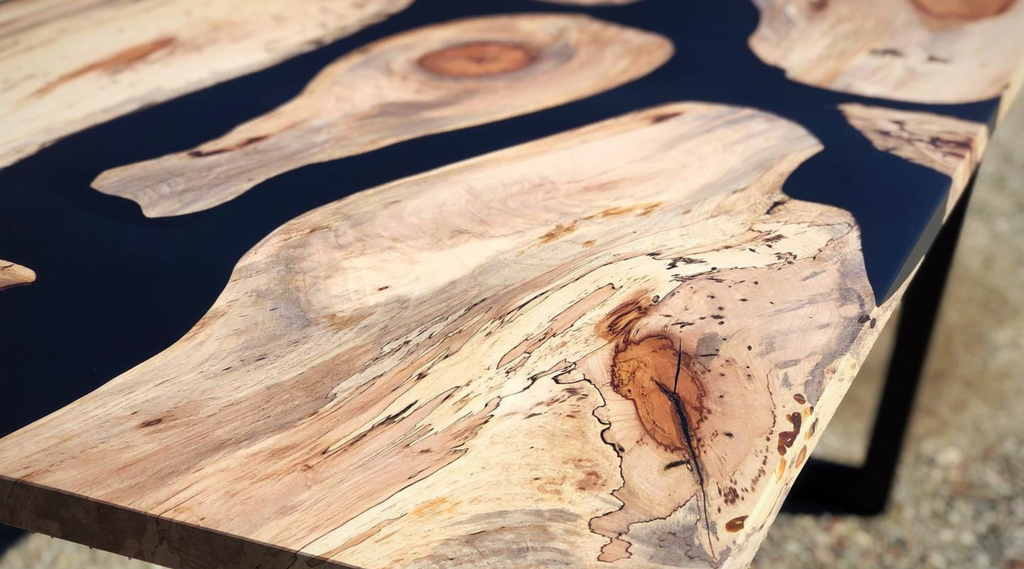walnut wood river table with black pigment dye to get colored epoxy sitting outside
