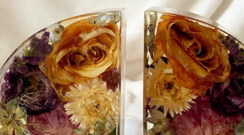 two resin bookends with flowers inside sitting against a cream fabric background