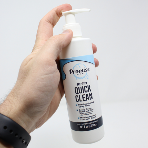 male hand holding a bottle of Promise Resin Quick Clean against a white background