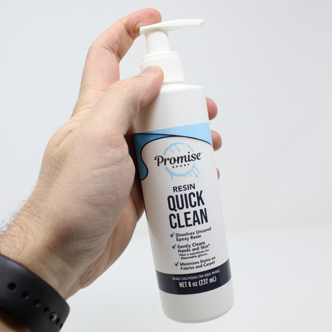 male hand holding a bottle of promise epoxy resin quick clean against a white background