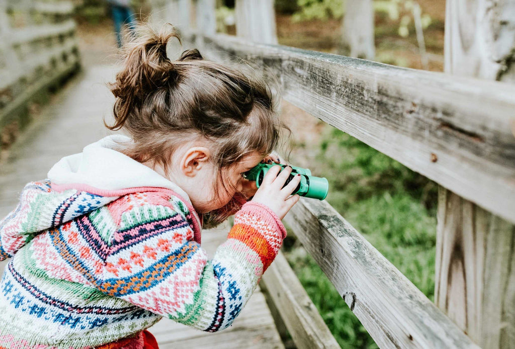 Girl looking through fence with binoculars