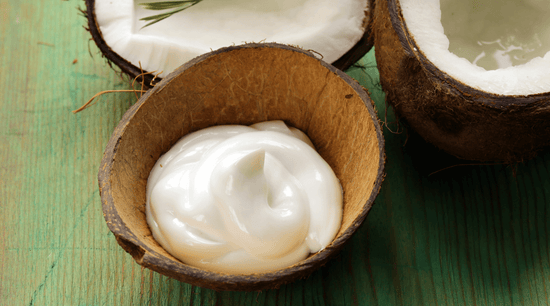 homemade moisturizer in a coconut shell beside coconut halves