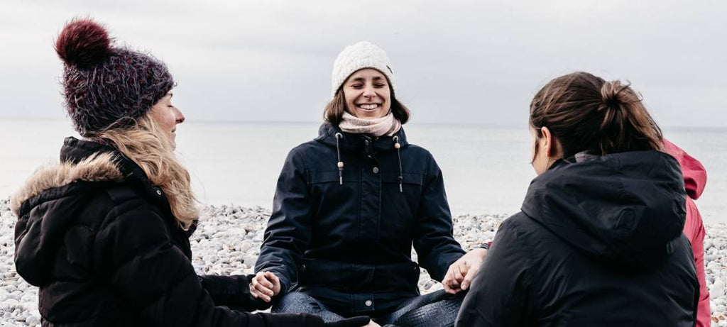 groupe de femmes faisant du yoga sur un plage l'hiver