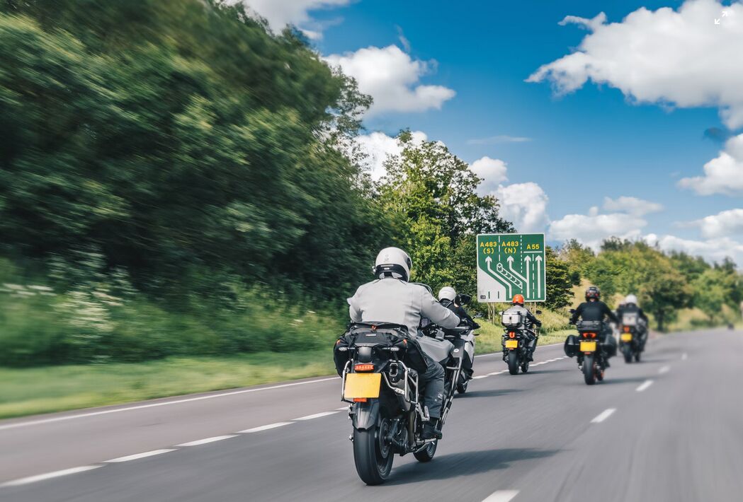 a group of people riding motorcycles down a road