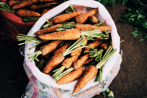 ripe carrots inside white net sack.