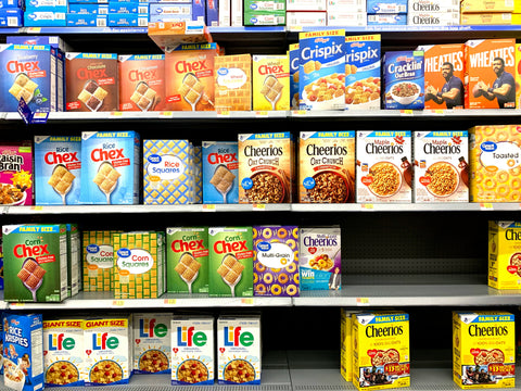 A grocery aisle filled with cardboard cereal boxes.