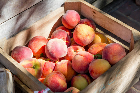 A wooden crate filled with ripe peaches.