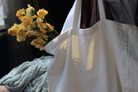 A cotton tote bag holding a small bouquet of yellow flowers.