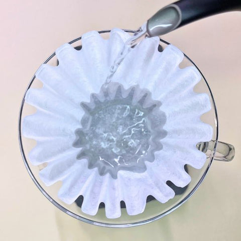 Rinsing a paper coffee filter with hot water