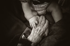 Older woman's hand holding infant's hand, black and white image