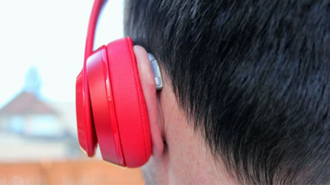 Person wearing headphones over their hearing aids.
