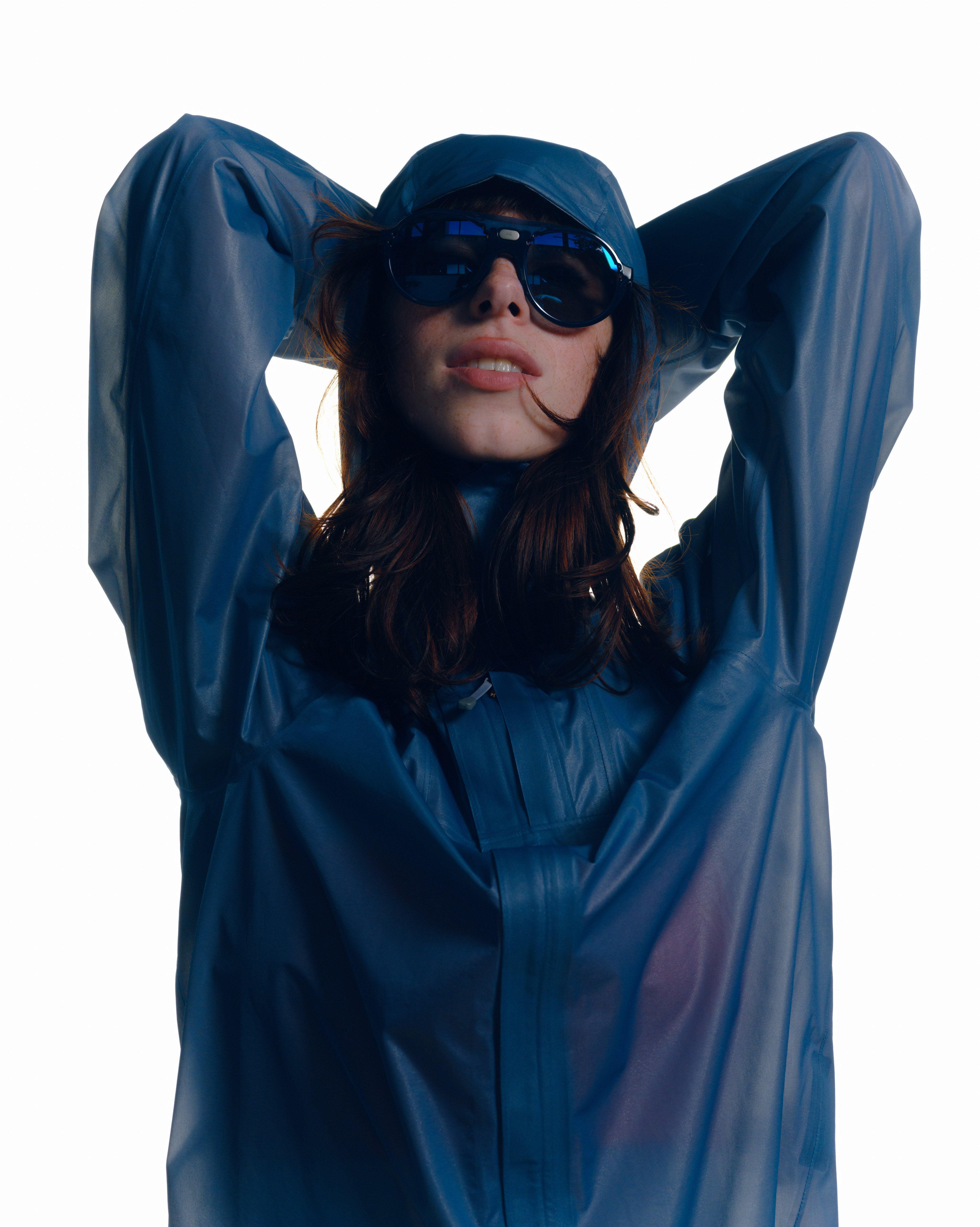 A woman wearing a Houdini jacket and District Vision sunglasses bra and tights