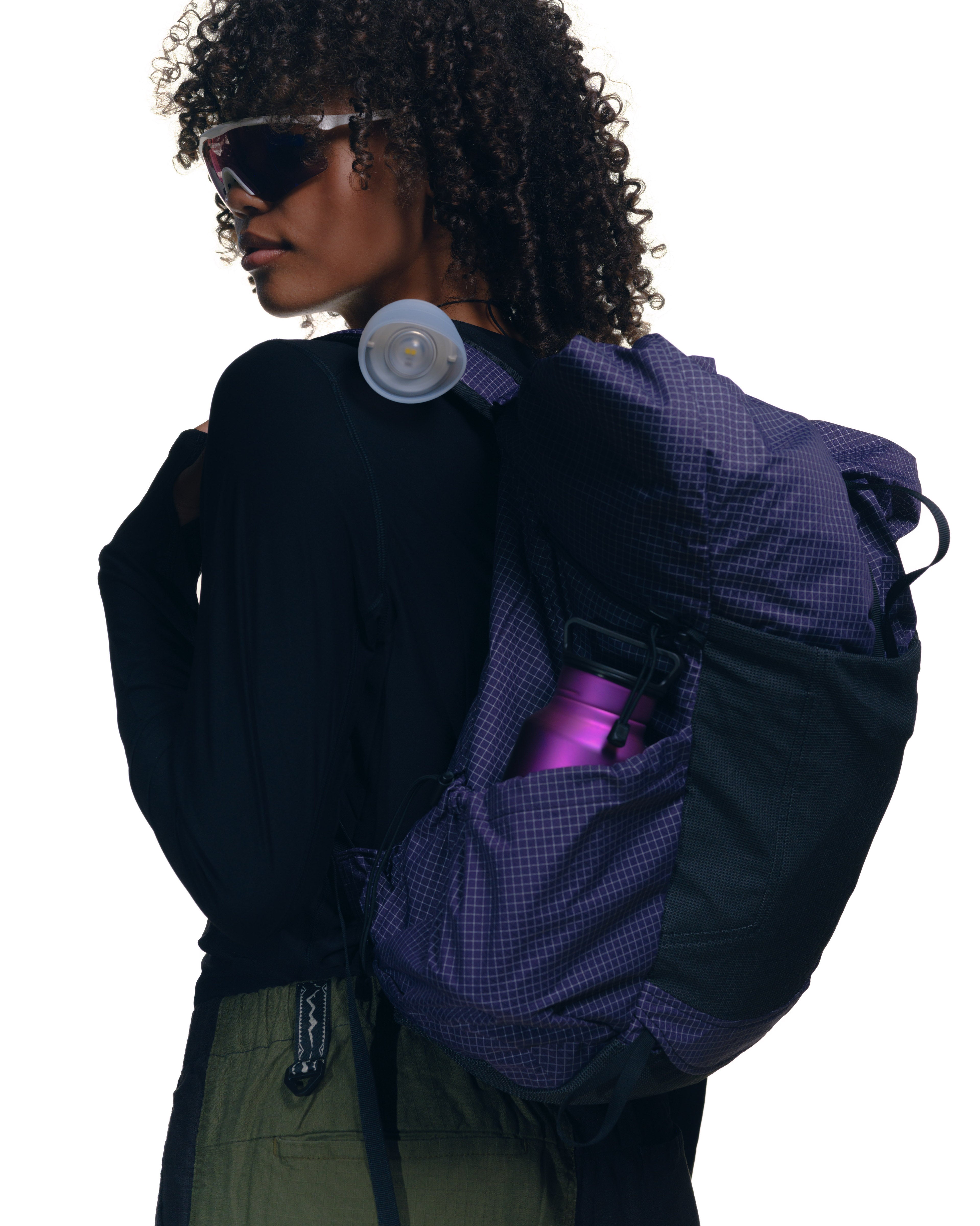 A woman wearing a Pa'lante Desert Pack with Snow Peak accessories and a District Vision top with Manastash pants and Alba Mantra sunglasses