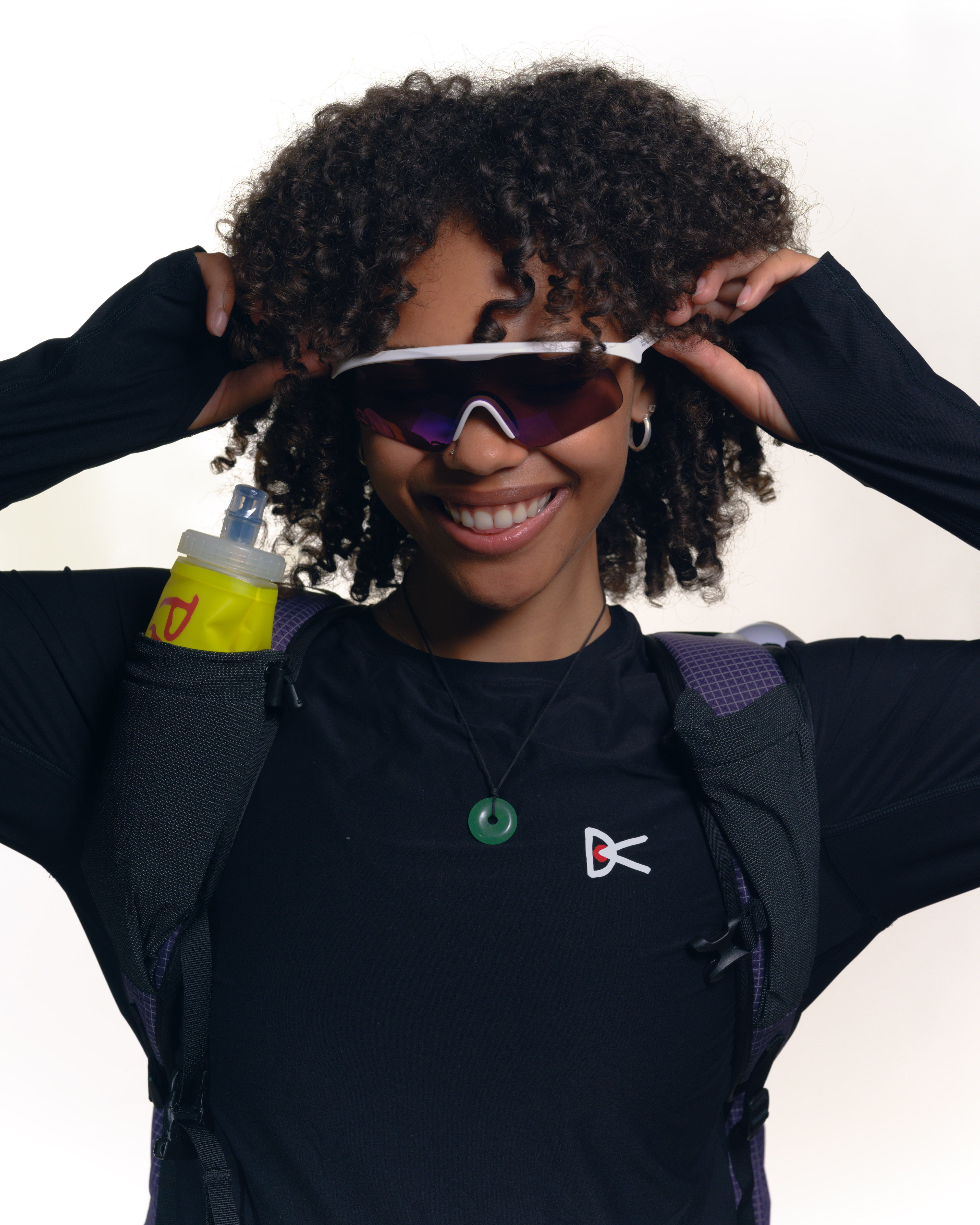 A woman wearing Alba Optics Mantra sunglasses, a Pa'lante Desert Pack and a District Vision top