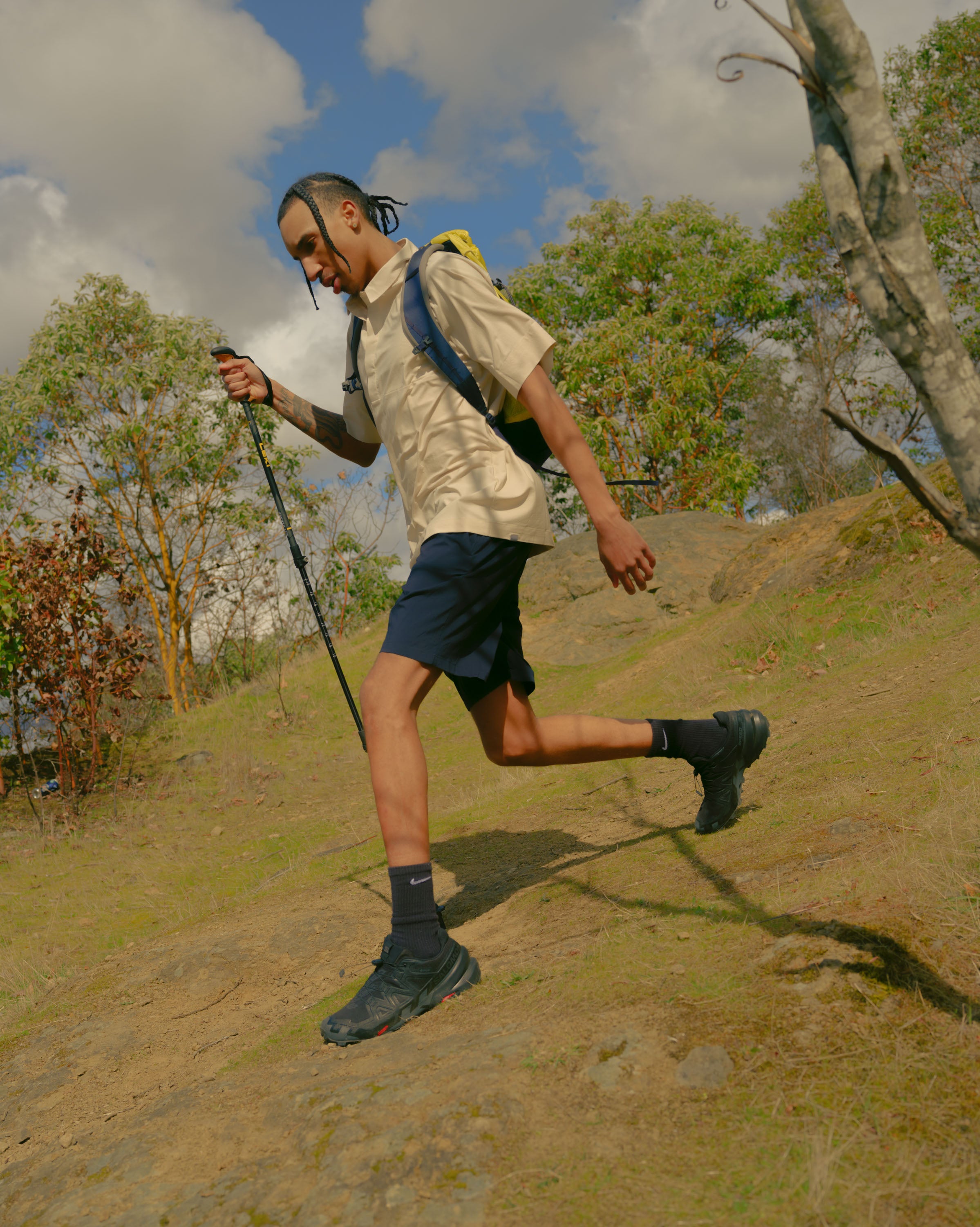 A man hiking down a hill with Leki poles and Houdini shirt and shorts