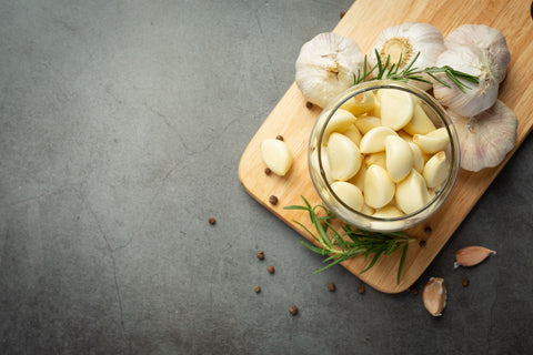 Fresh garlic clove surrounded by immune-boosting supplements, showcasing allicin's role in natural immune defense against cold and flu.
