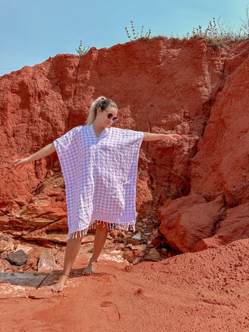 Blond girl dancing in purple kaftan in front of red rocks in wetsern australia. organic cotton changing robes, each robe, beach tunic