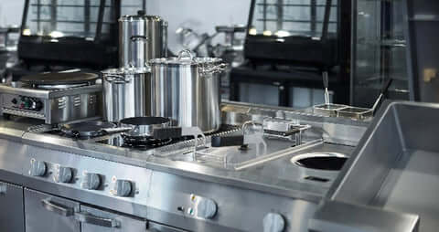 Clean pots and pans sit atop a range in a commercial kitchen