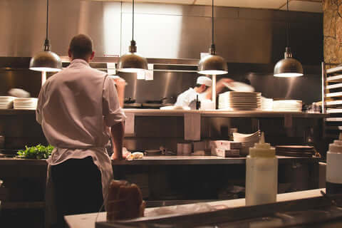 A chef and cooks work in a commercial kitchen