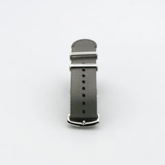 Grey nylon watch strap with black stripes displayed on a table - a sleek and durable watch accessory for any occasion.