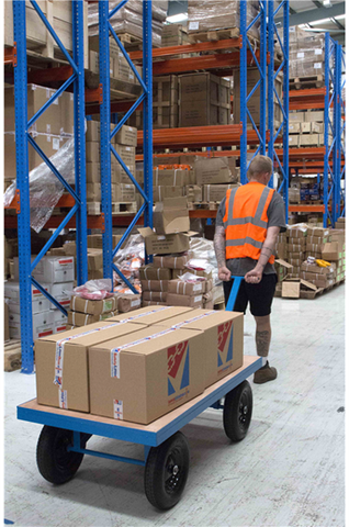 A warehouse worker pulling a trolley safely with the use of industrial trolley wheels.