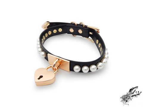 black and gold choker made of vegan leather, with a gold heart padlock in the centre and white pearl studs around either side