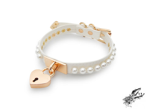 white and gold choker made of vegan leather, with a gold heart padlock in the centre and white pearl studs around either side