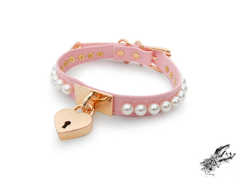 pink and gold choker made of vegan leather, with a gold heart padlock in the centre and white pearl studs around either side