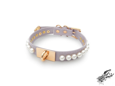 lilac and gold choker made of vegan leather, with a gold hardware plate with U shaped stud in the centre and white pearl studs around either side